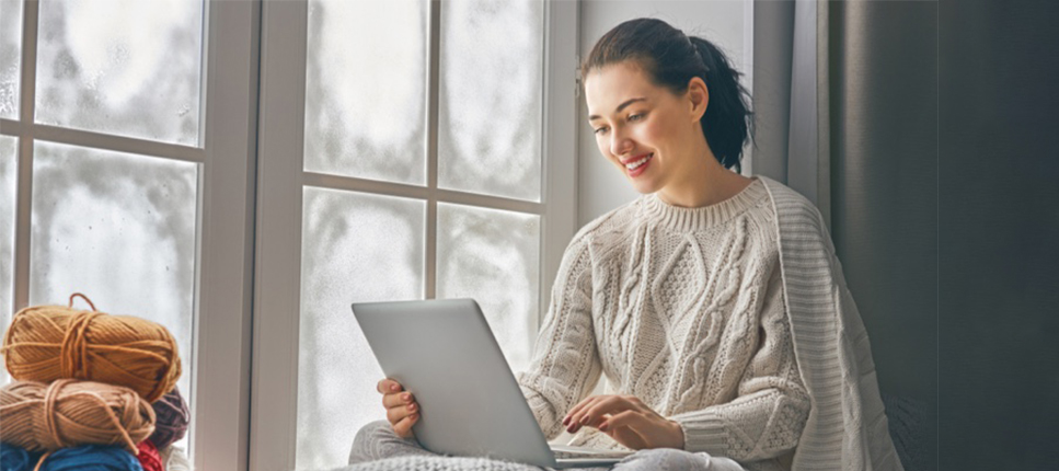 happy women looking at a laptop by window in home