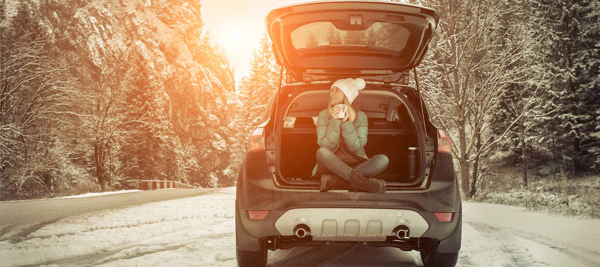 happy woman sitting in car on snow covered road